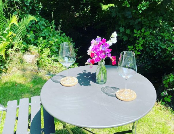 Table and chairs bathed in sunlight next to the burbling stream